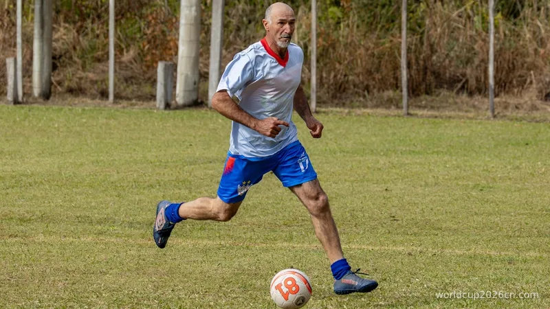 Athletic man playing soccer on a green field.